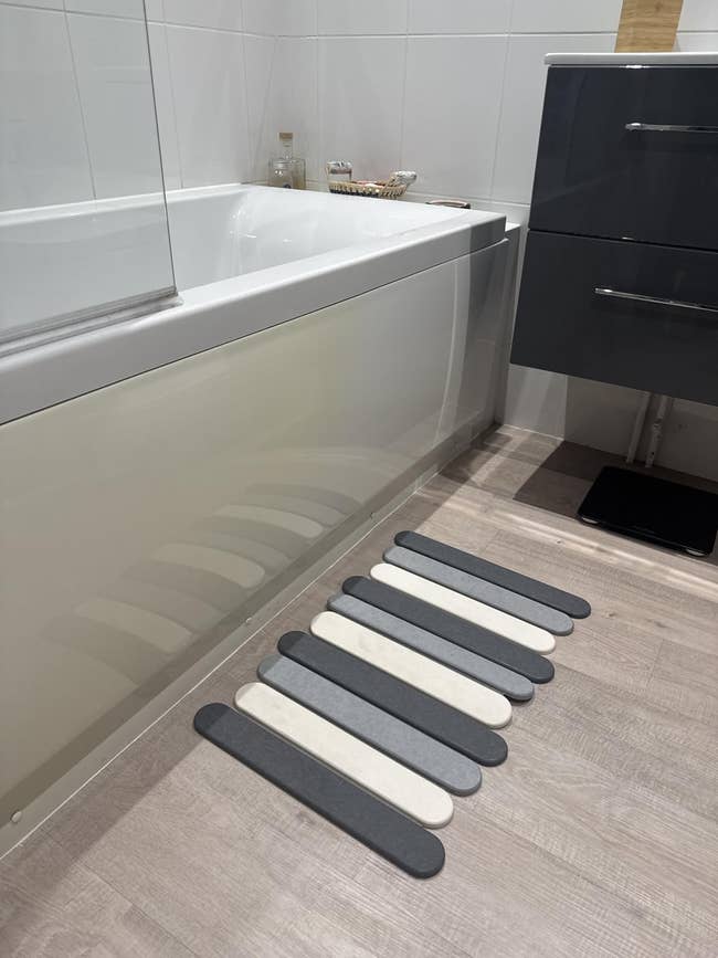 Modern bathroom with a bathtub and a striped non-slip rug on the floor, perfect for stylish and safe decor