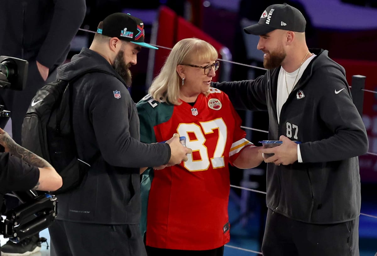 PHOENIX, ARIZONA - FEBRUARY 06: Mother Donna Kelce (C) gives cookies to her son's Jason Kelce (L) #6