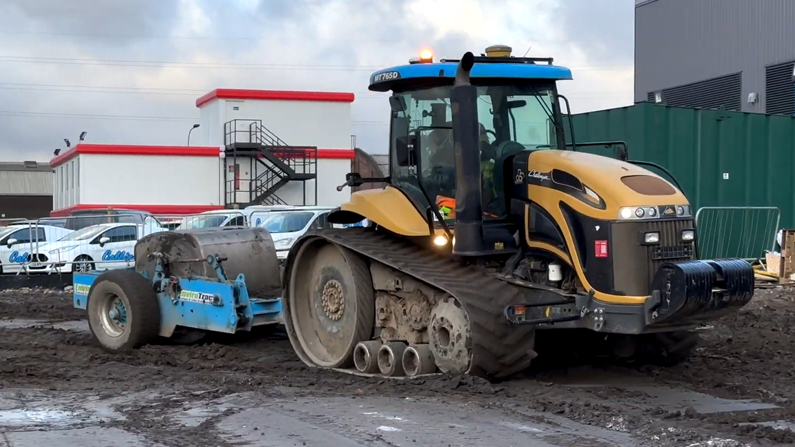 Grote rups tractor trekt zware wals door diepe modder