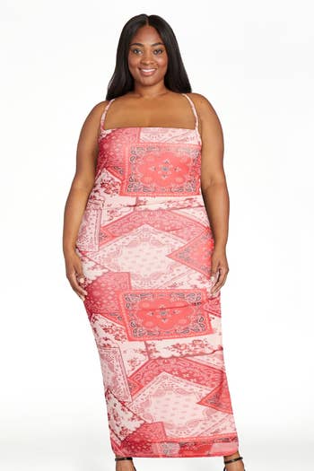 A person poses in a patterned dress with spaghetti straps and intricate floral designs, suitable for a stylish, casual look