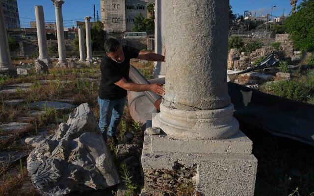 Adnan Istanbuli, an employee at the Directorate General of Antiquities, inspects a Roman-era column after part of its capital was knocked off and fell to the ground at an archaeological site lightly damaged in an Israeli strike, in the southern port city of Tyre, Lebanon, June 18, 2026. (AP Photo/Hassan Ammar)
