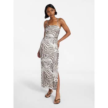 Person wearing a zebra-patterned sleeveless dress with thin straps, standing in a relaxed pose, paired with simple sandals