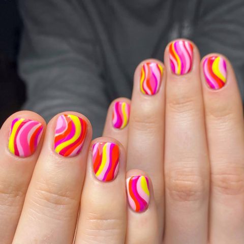 Closeup of hands with nails featuring vibrant wavy designs