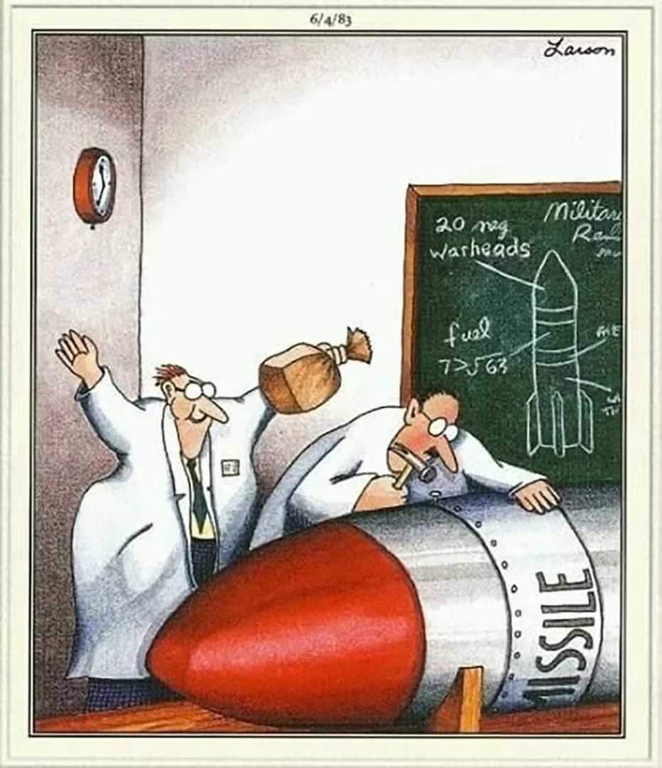 One scientist working on a bomb with a hammer while another prepares to pop a paper bag right behind them as a prank