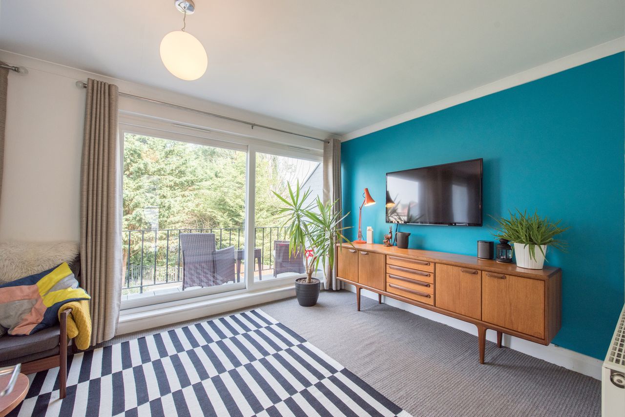 Living room with teal accent wall and black and white striped rug