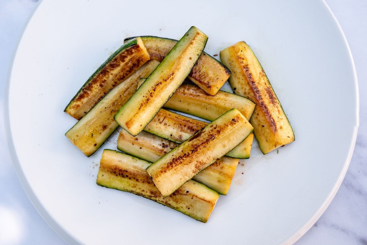 Sauted zucchini slices arranged on a white plate