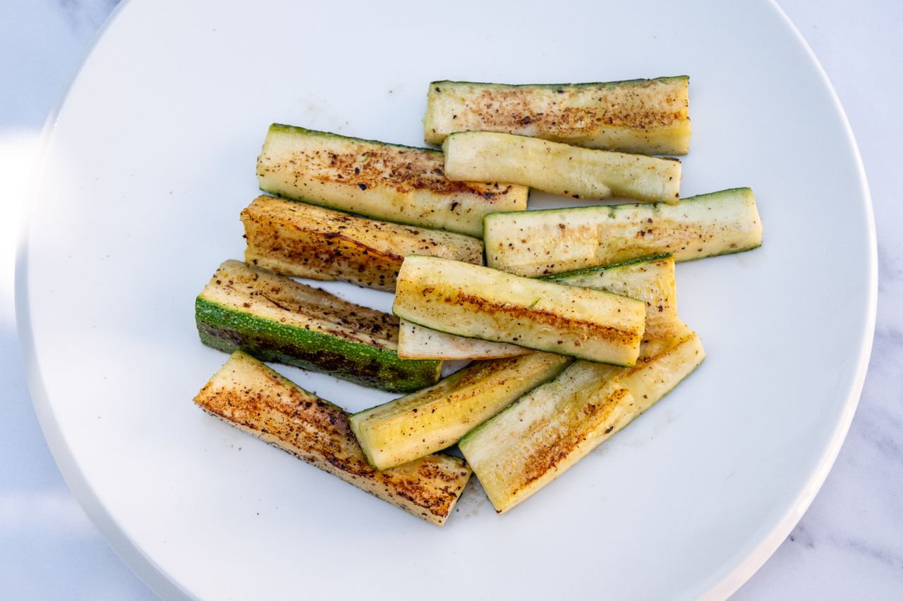 Grilled zucchini slices arranged on a white plate