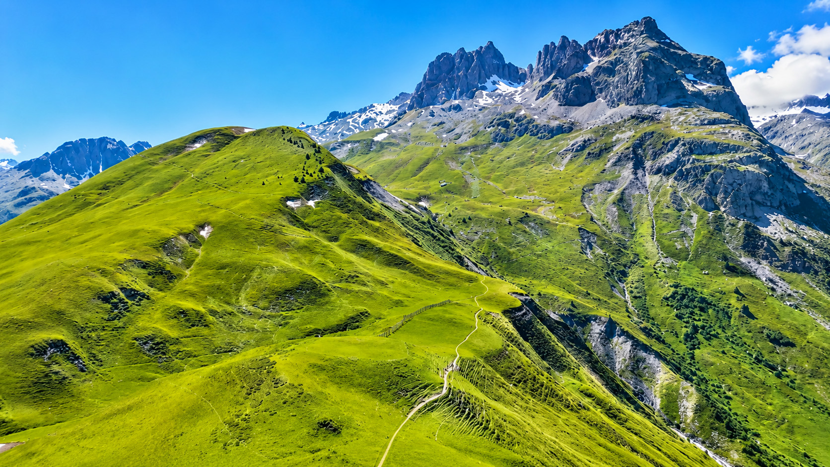 The French Alps rising above endless green hills