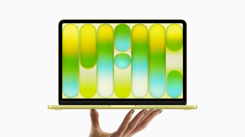 A hand holding a MacBook Neo