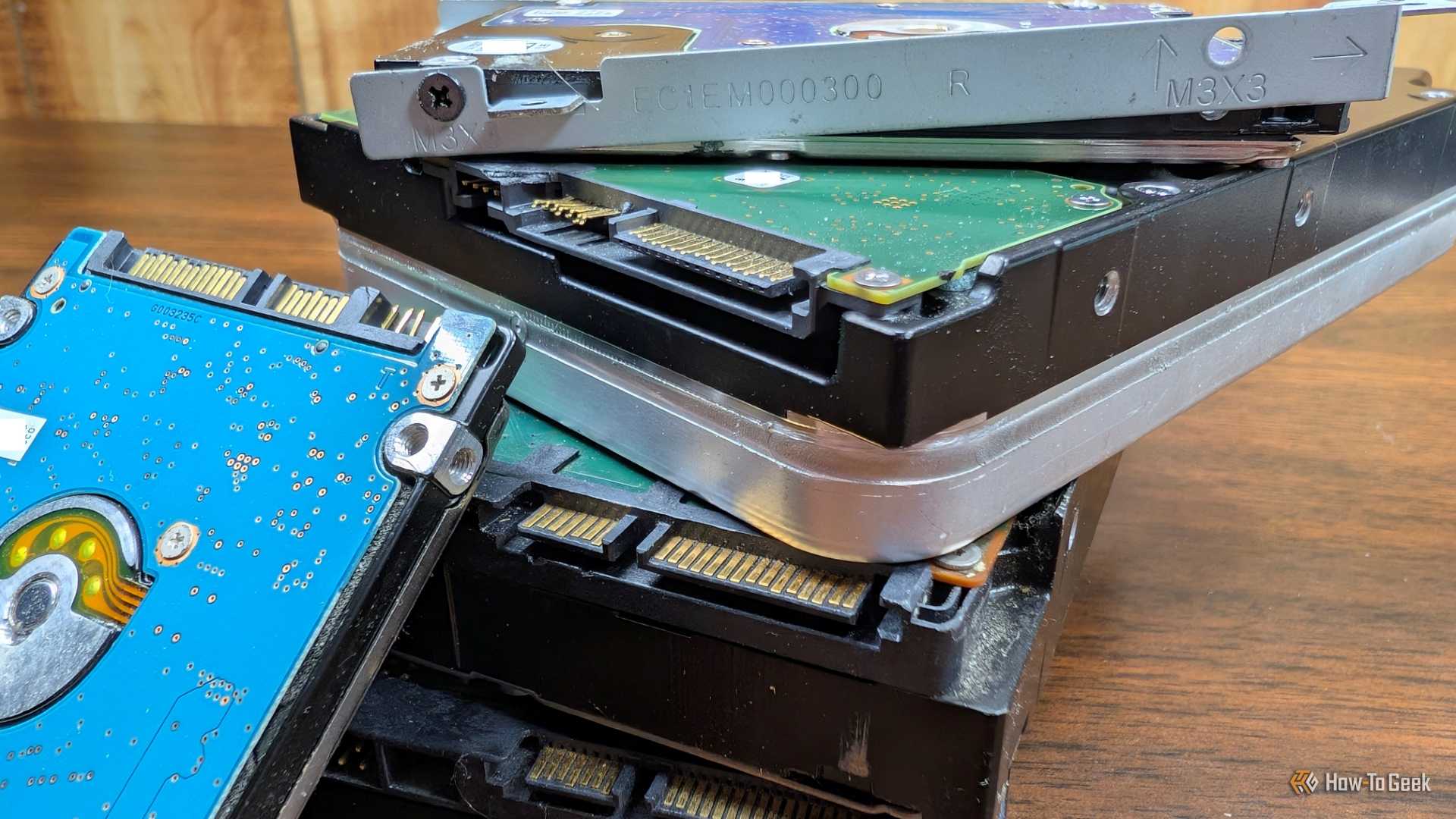 A laptop hard drive leaning against several desktop hard drives.