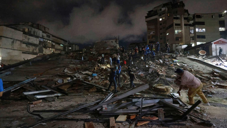 Rescue workers search through the rubble in Caracas (Javier Campos/AP)