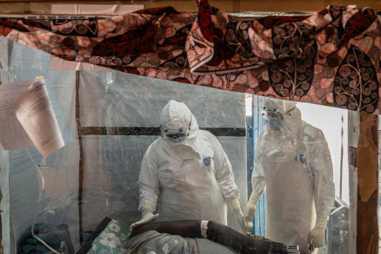 Health workers tend to an Ebola patient at the Rwampara Treatment Center in Ituri, Congo