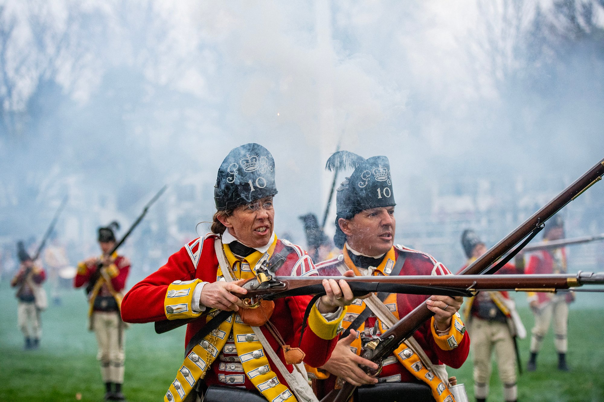 Reenactors dressed as a British soldiers fire during a battle reenactment of the Battle of Lexington and Concord.