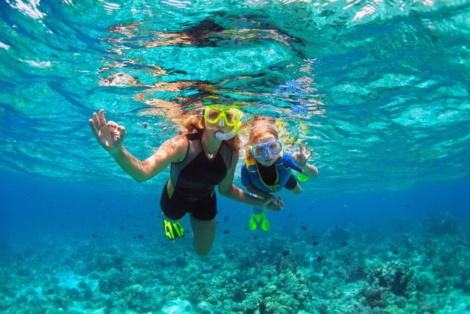Mother, Kid In Snorkeling Mask Dive Underwater With Tropical Fishes
