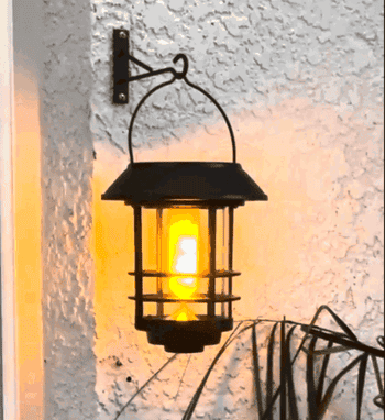 A lantern with a flickering flame effect mounted on a textured wall, offering a vintage aesthetic for outdoor decor