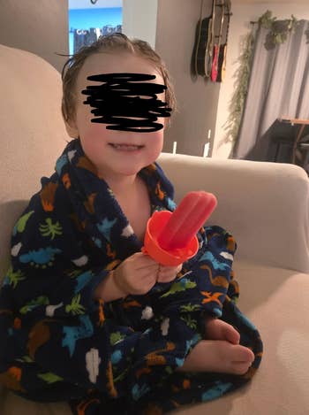 child sitting on a couch eating a popsicle from the holder