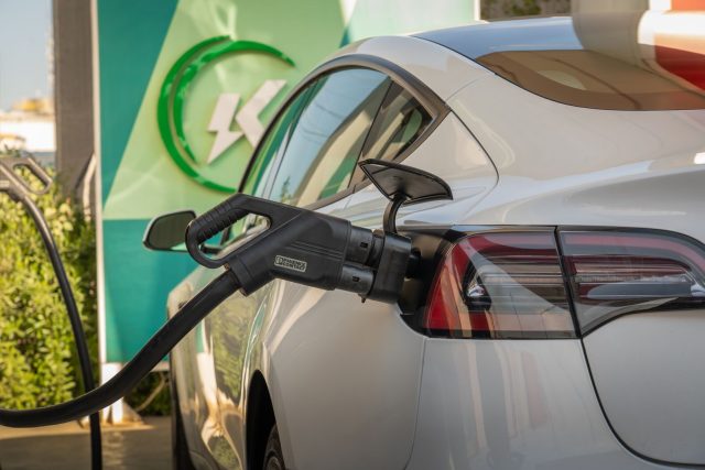 Close-up of Tesla Model 3 connected to a charging station, highlighting eco-friendly transportation.