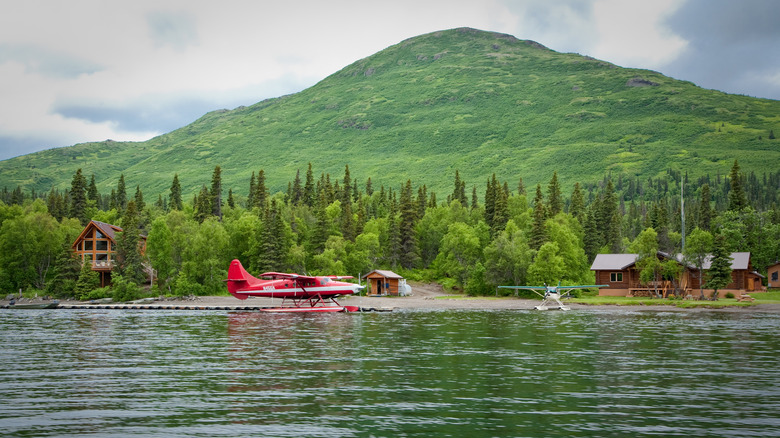 A floatplane lands on the Agulowak River in Wood-Tikchik State Park, with a green hill seen behind