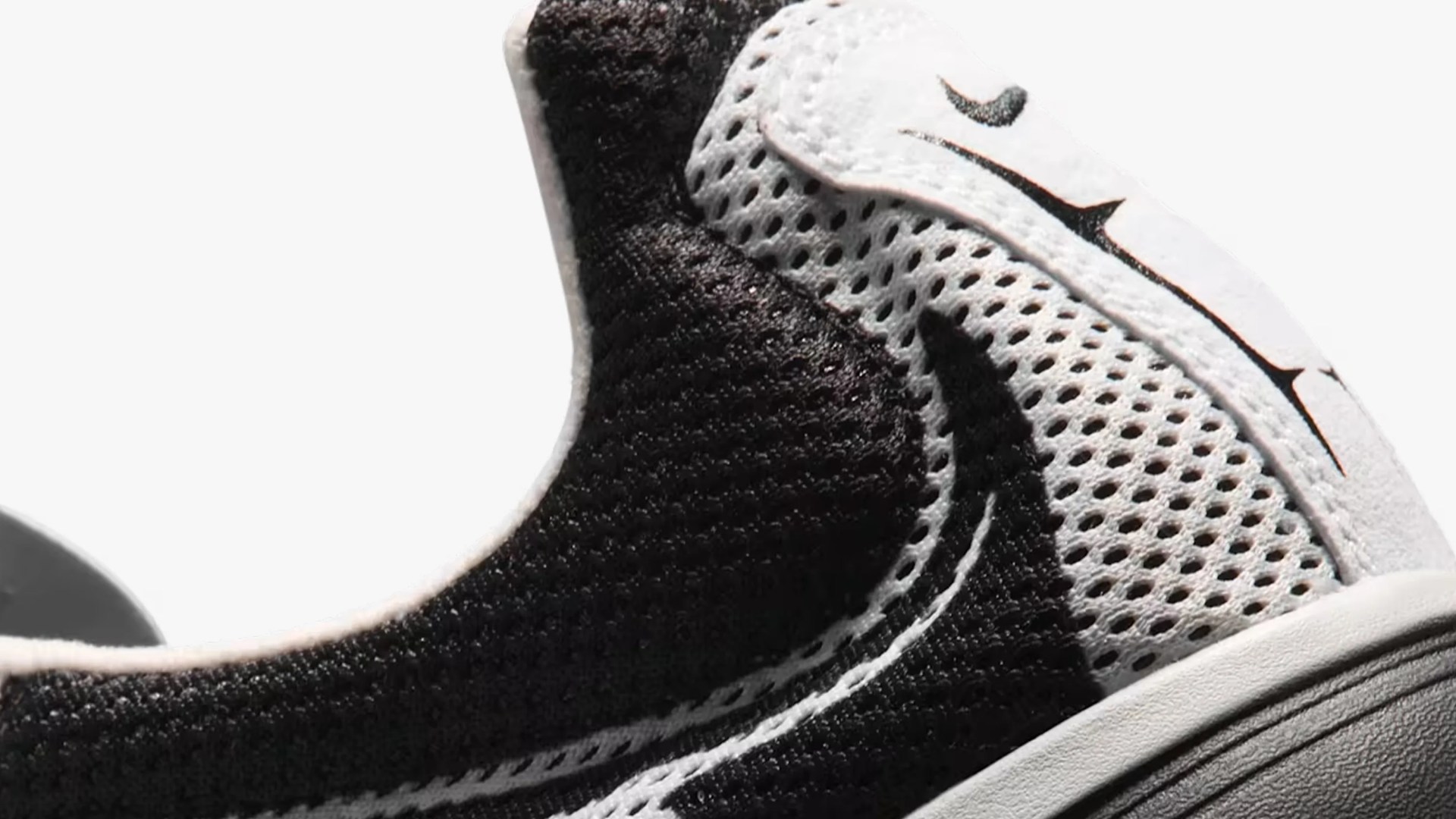 Close-up of a black and white Nike sneaker with mesh fabric and a visible Nike swoosh logo.