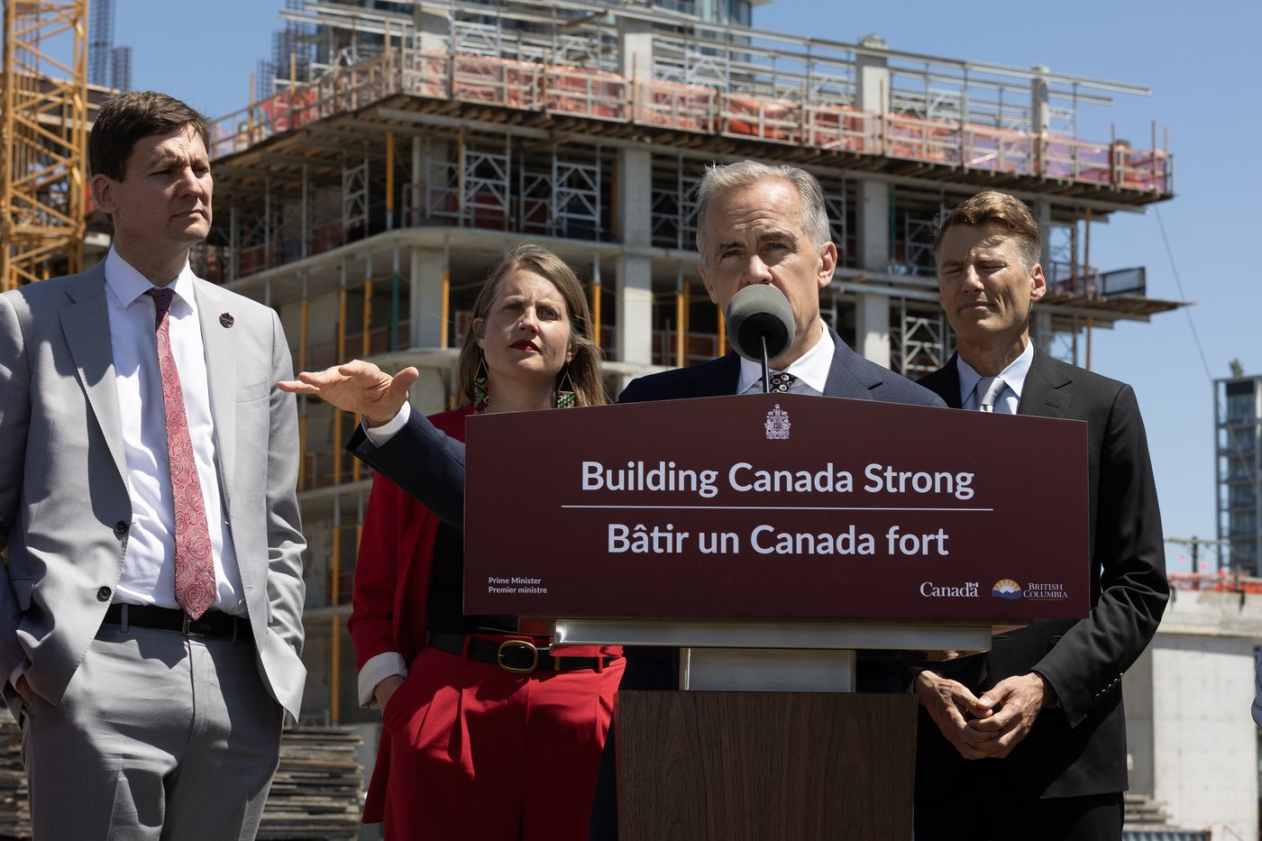 B.C. Premier David Eby (left), provincial Housing Minister Christine Boyle and federal Housing Minister Gregor Robertson (right) look on as Prime Minister Mark Carney makes an announcement at a construction site in Vancouver on Thursday, June 18, 2026. THE CANADIAN PRESS/Chad Hipolito