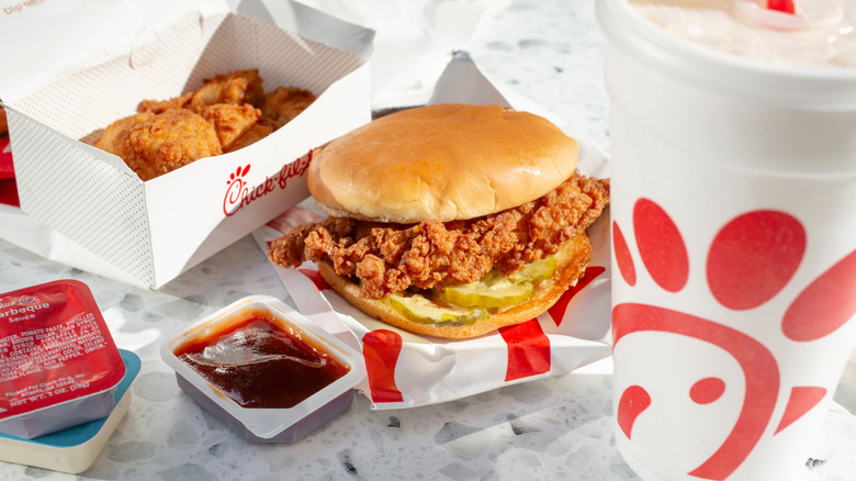 Chick-fil-A sandwich on wrapper next to open sauce packet