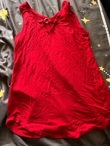 Red tank top with a decorative ring detail at the neckline, laid on a bed with star patterns