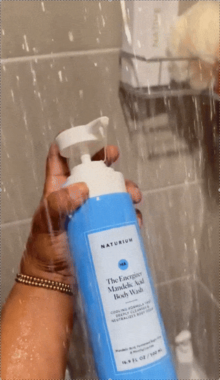 Person using Naturium The Energiere Mandelic Acid Body Wash in a shower