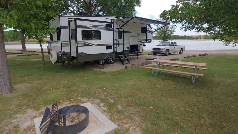 A trailer parked at the campsite at the Webster State Park campground, with a fire ring and picnic table outside