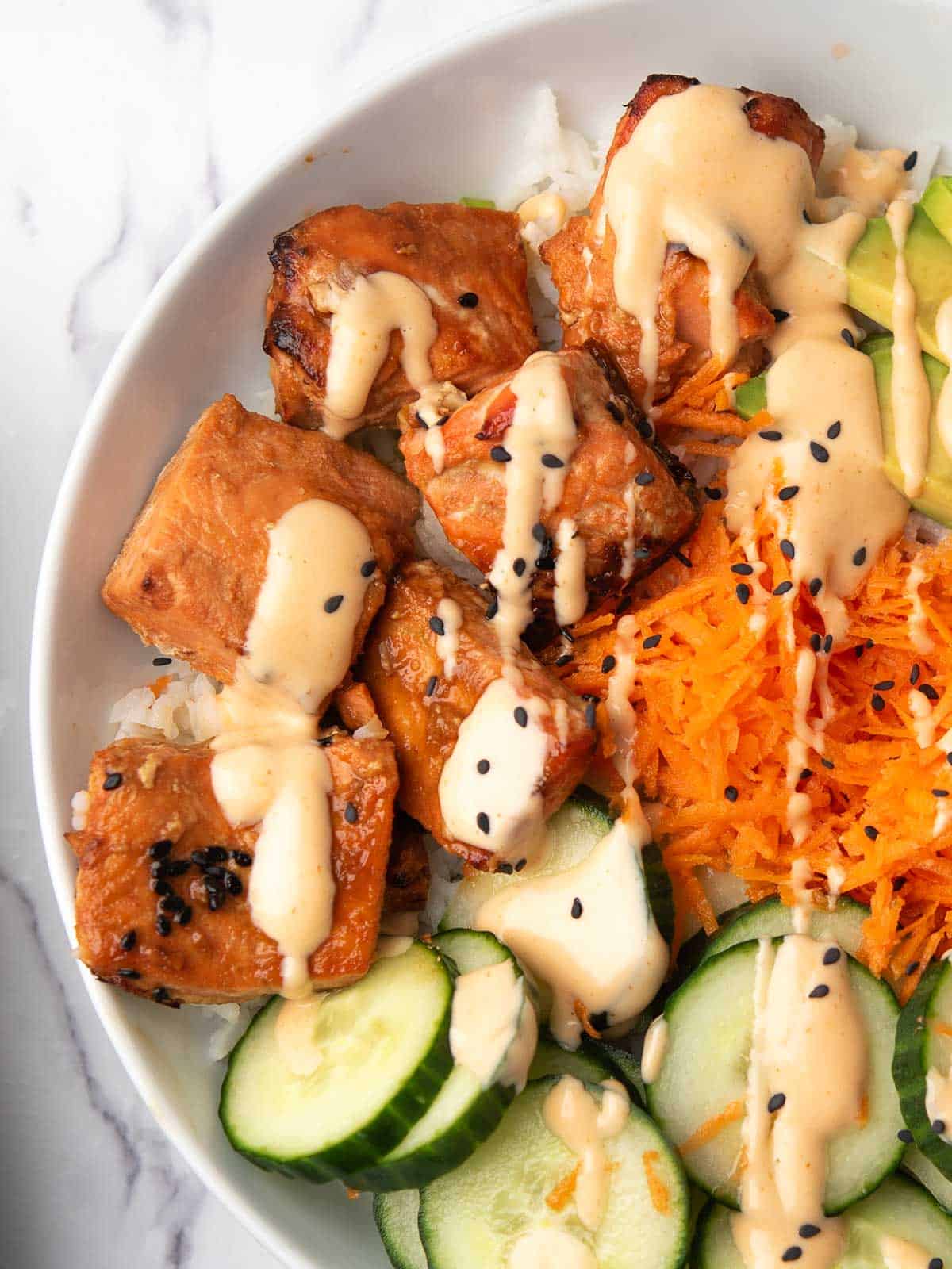 the flacky spicy salmon bowl, drizzled with spicy mayo, a close up view.