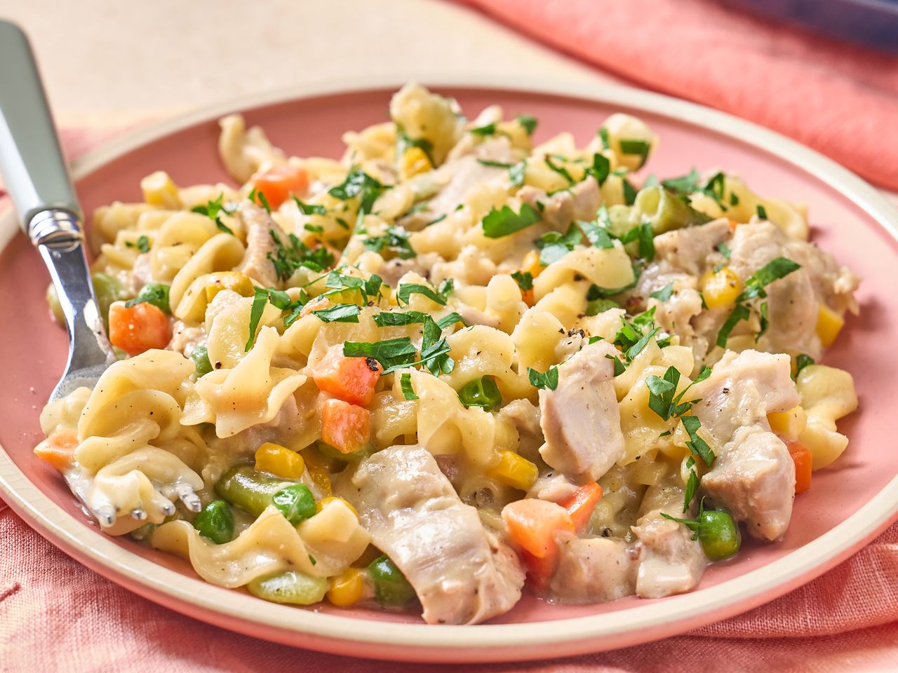 A plate of creamy chicken pasta with vegetables and parsley