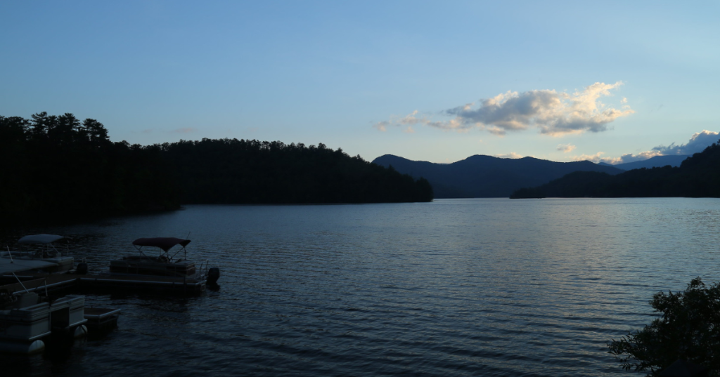 Santeelah Lake at dusk, with mountains and trees surrounding under a dark blue sky.