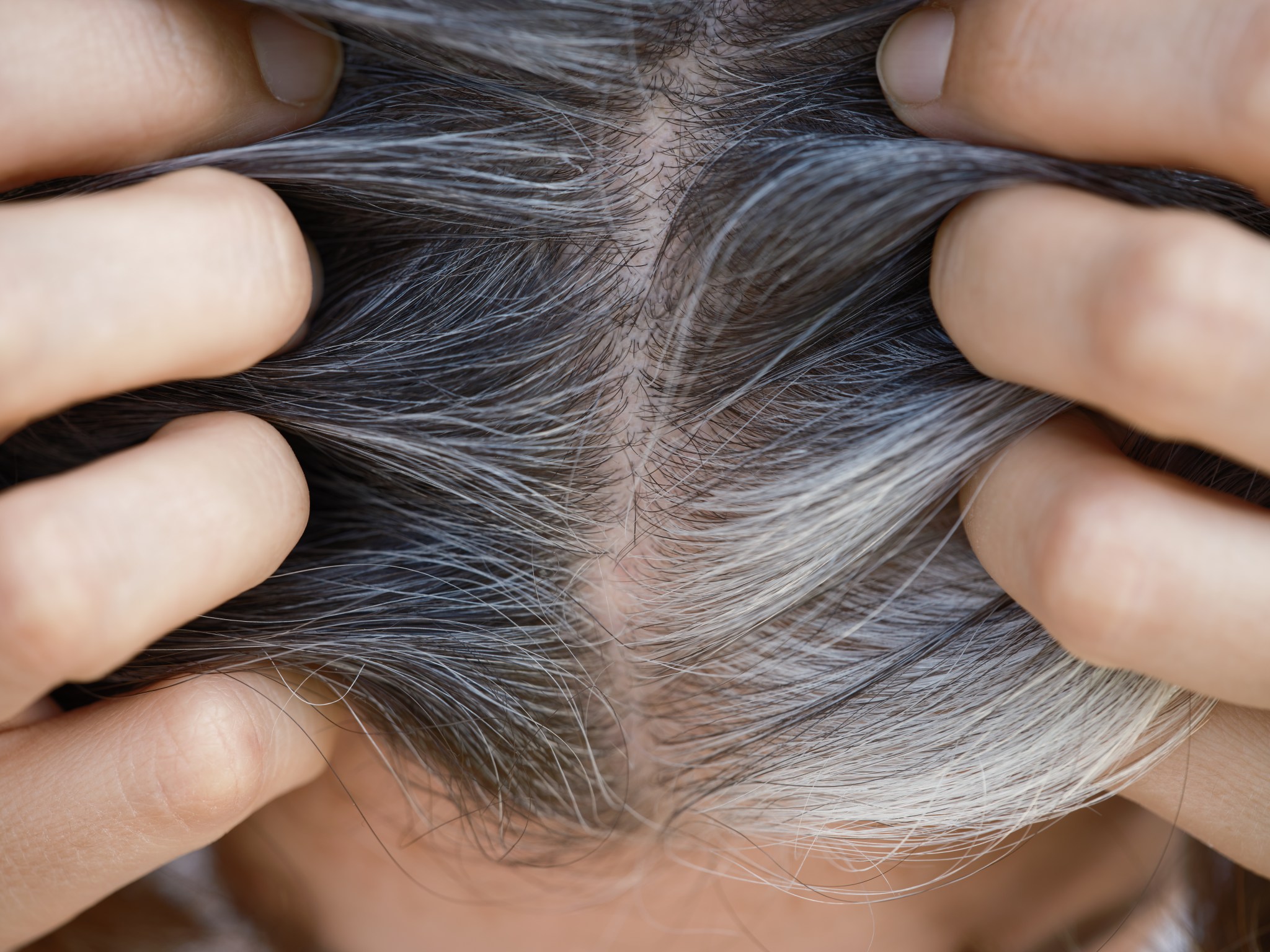 A woman showing her gray hair roots