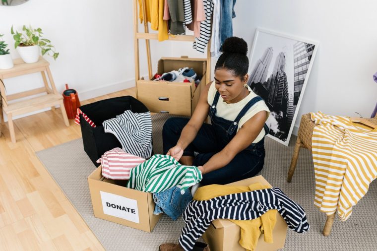 Young Latin American woman preparing clothes for a donation or recycling, donate, charity and generosity concept
