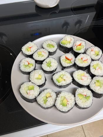 Plate of sliced sushi rolls filled with cucumber and imitation crab, placed on a stovetop