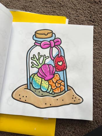 Illustration of colorful seashells and coral in a jar with a pink bow and heart tag, resting on sand