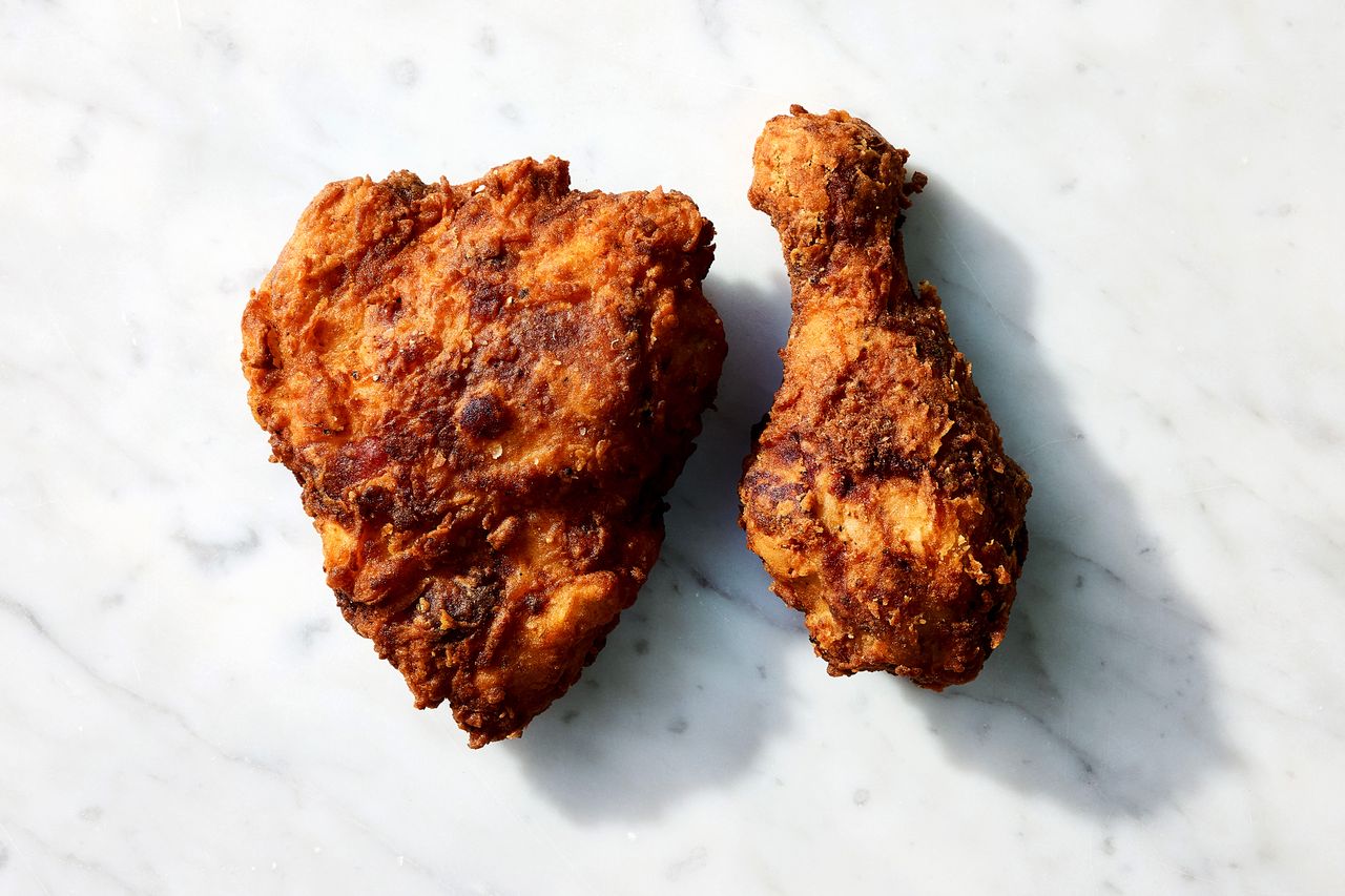 A piece of fried chicken breast and drumstick on a marble surface