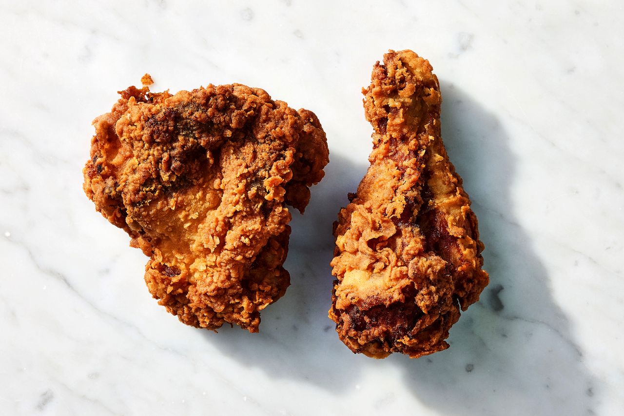 Two pieces of fried chicken displayed on a marble surface