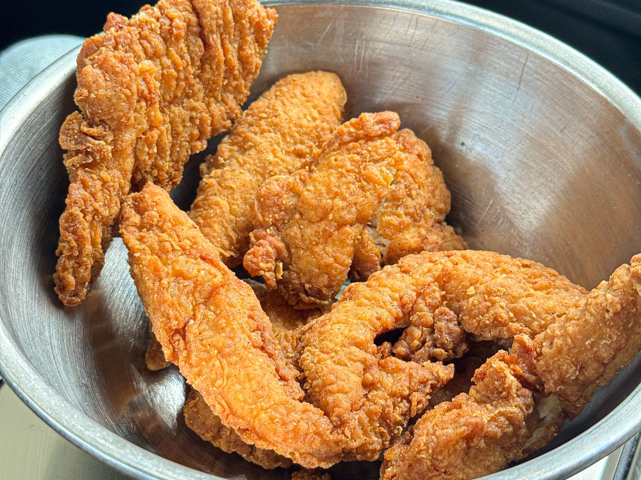 A metal bowl containing several pieces of fried chicken tenders