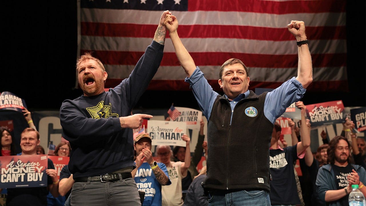 Democratic U.S. Senate candidate Graham Platner and Troy Jackson stand together during a "Fighting Oligarchy" tour stop at the Collins Center for the Arts on the University of Maine campus in Orono, Maine, on May 24, 2026.
