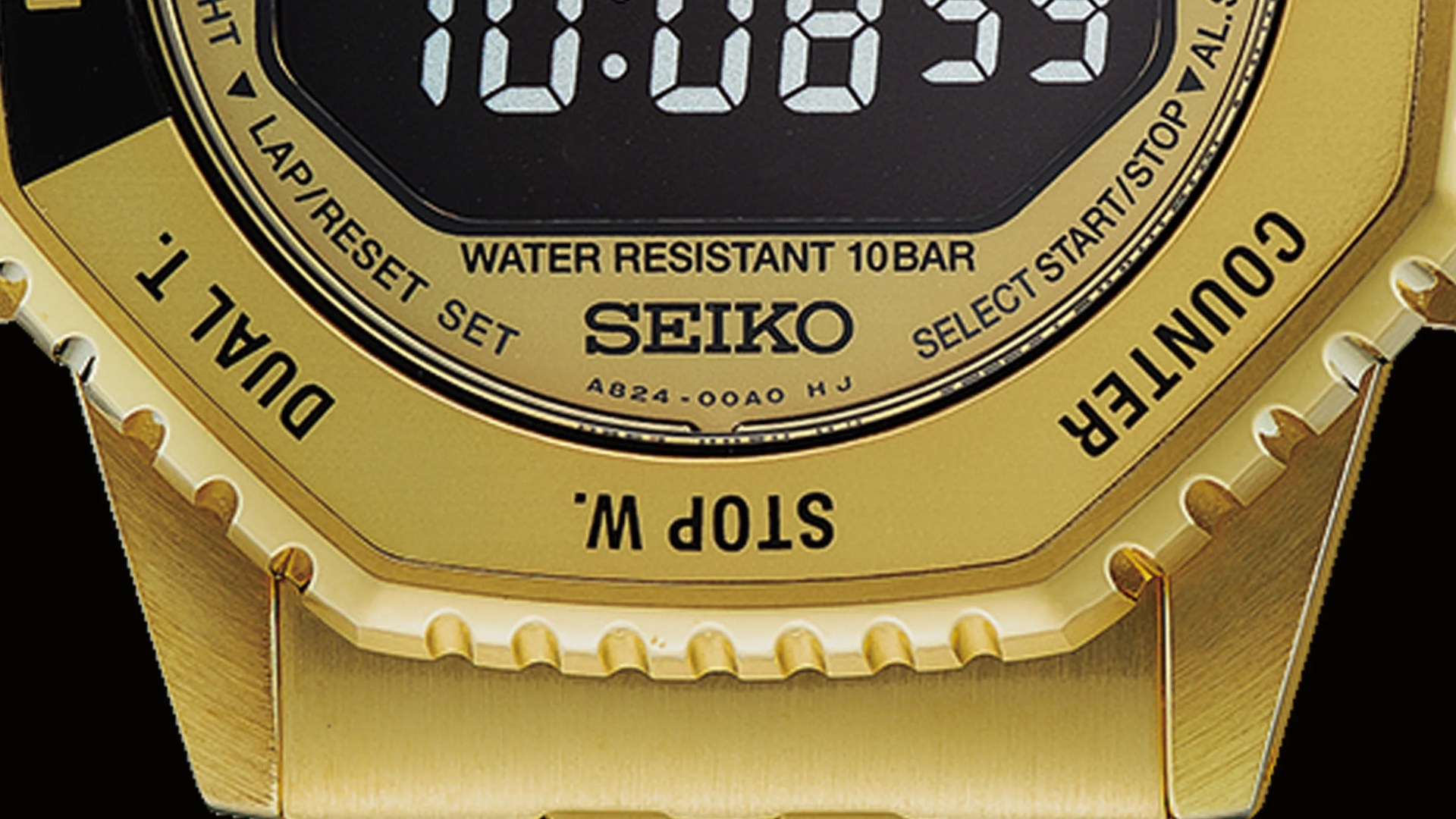 Close-up of a gold Seiko digital watch face showing water resistance, buttons, and part of the metal band.