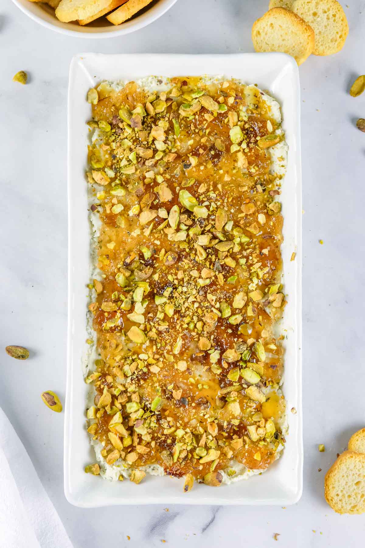 Rectangular white dish of Boursin cheese dip topped with chopped pistachios.