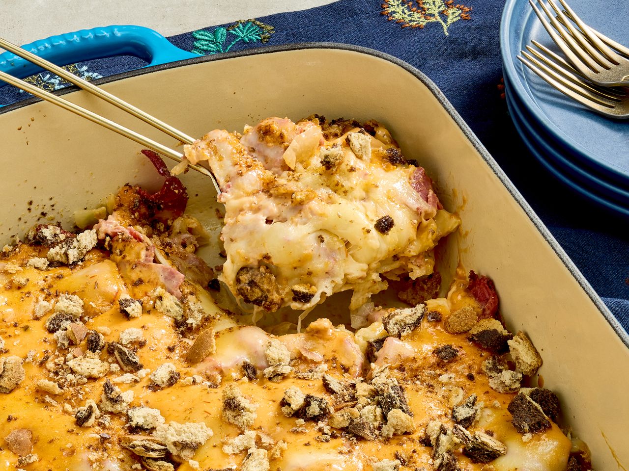 A baked casserole dish with a serving being lifted showing layers and topping