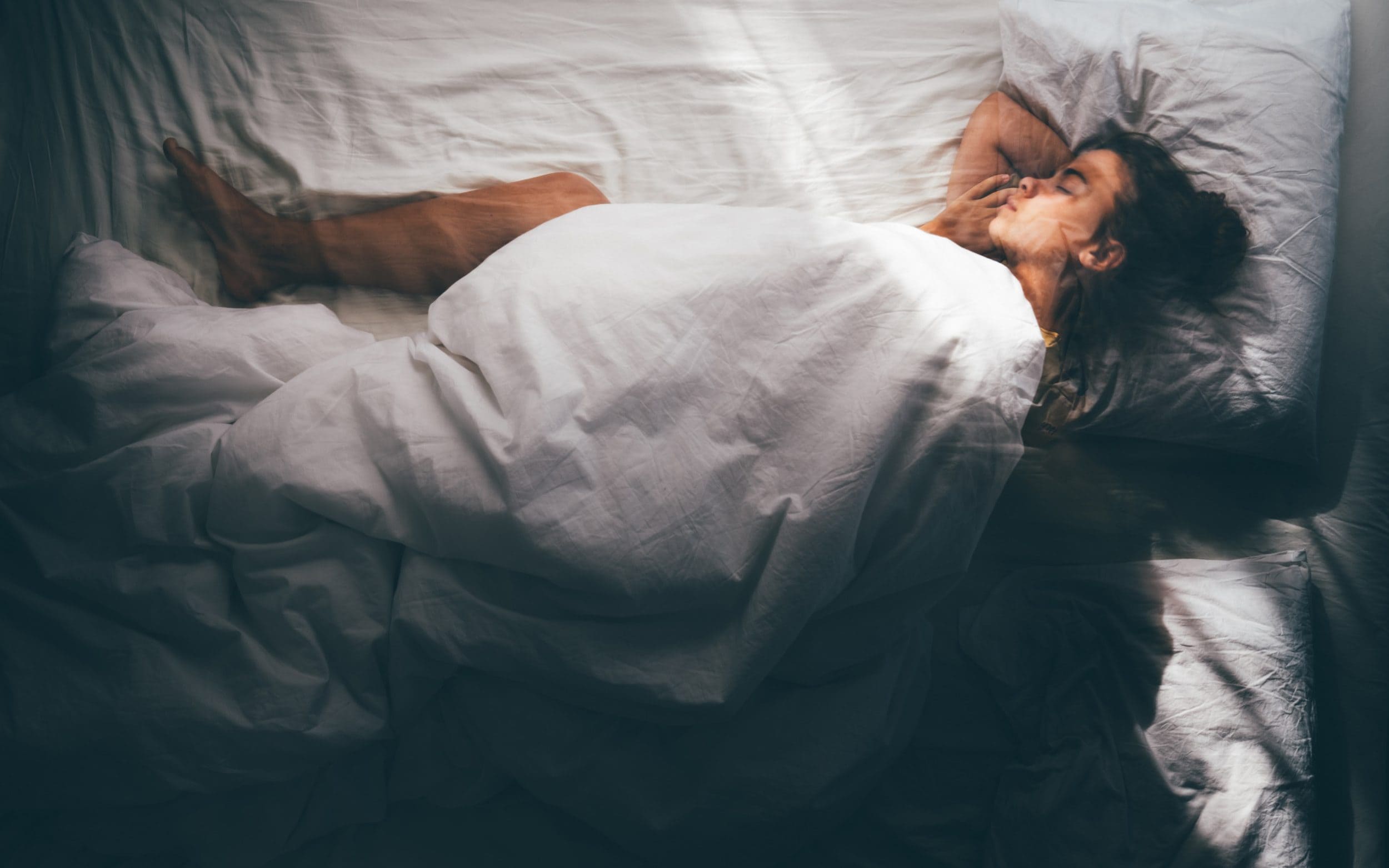 A woman sleeping under white covers