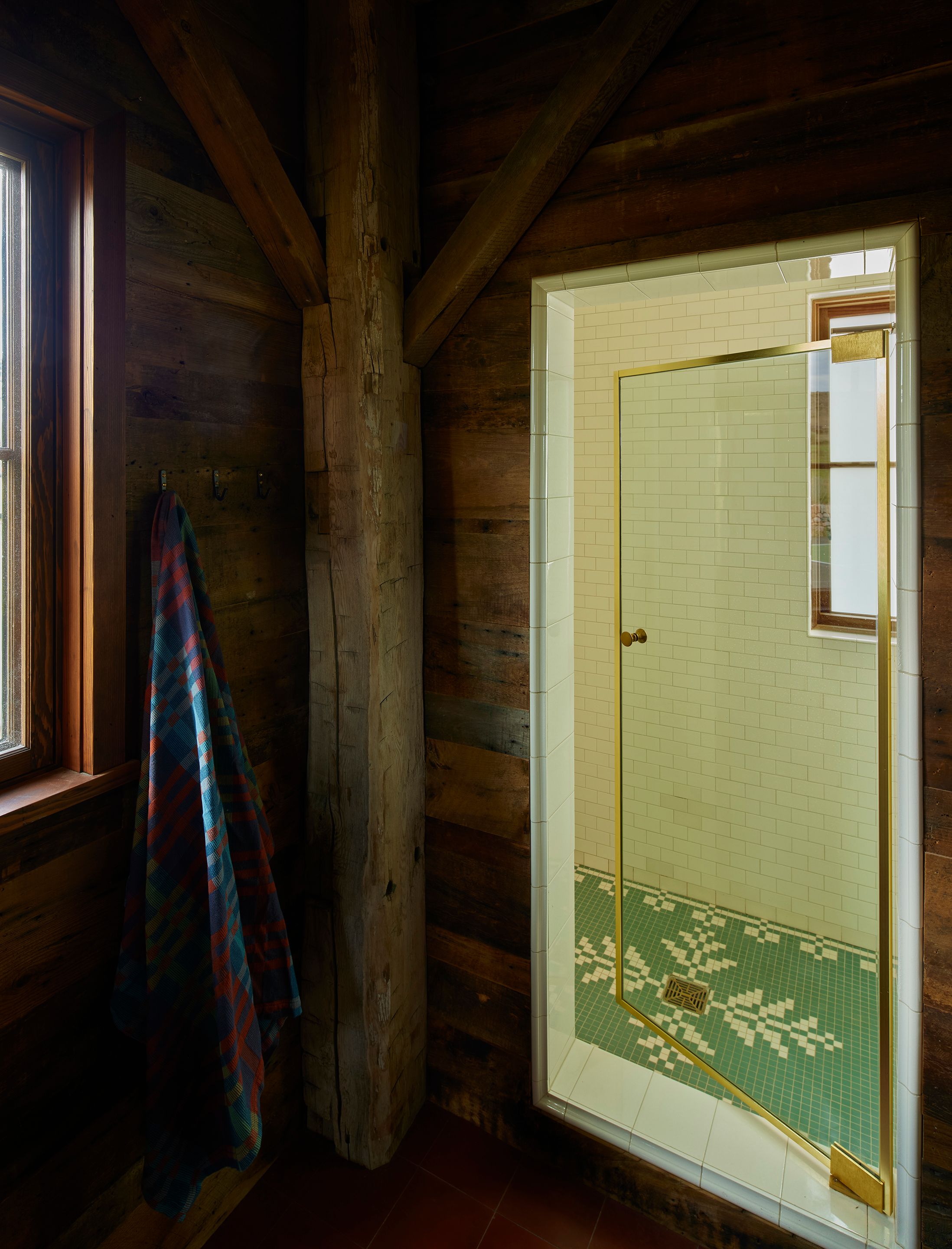 Beneath bright tiles from Subway Ceramics in crackle white is a custom mosaic designed by Landed Interiors in Heritage Tile that draws on traditional textile patterns to continue a quilt theme that emerged throughout the home. A Mungo Fido dog blanket in Toto hangs from a Brown hook by Mark Lewis Interior Design. Floors are cement tile in Chimayo by Zia Tile.