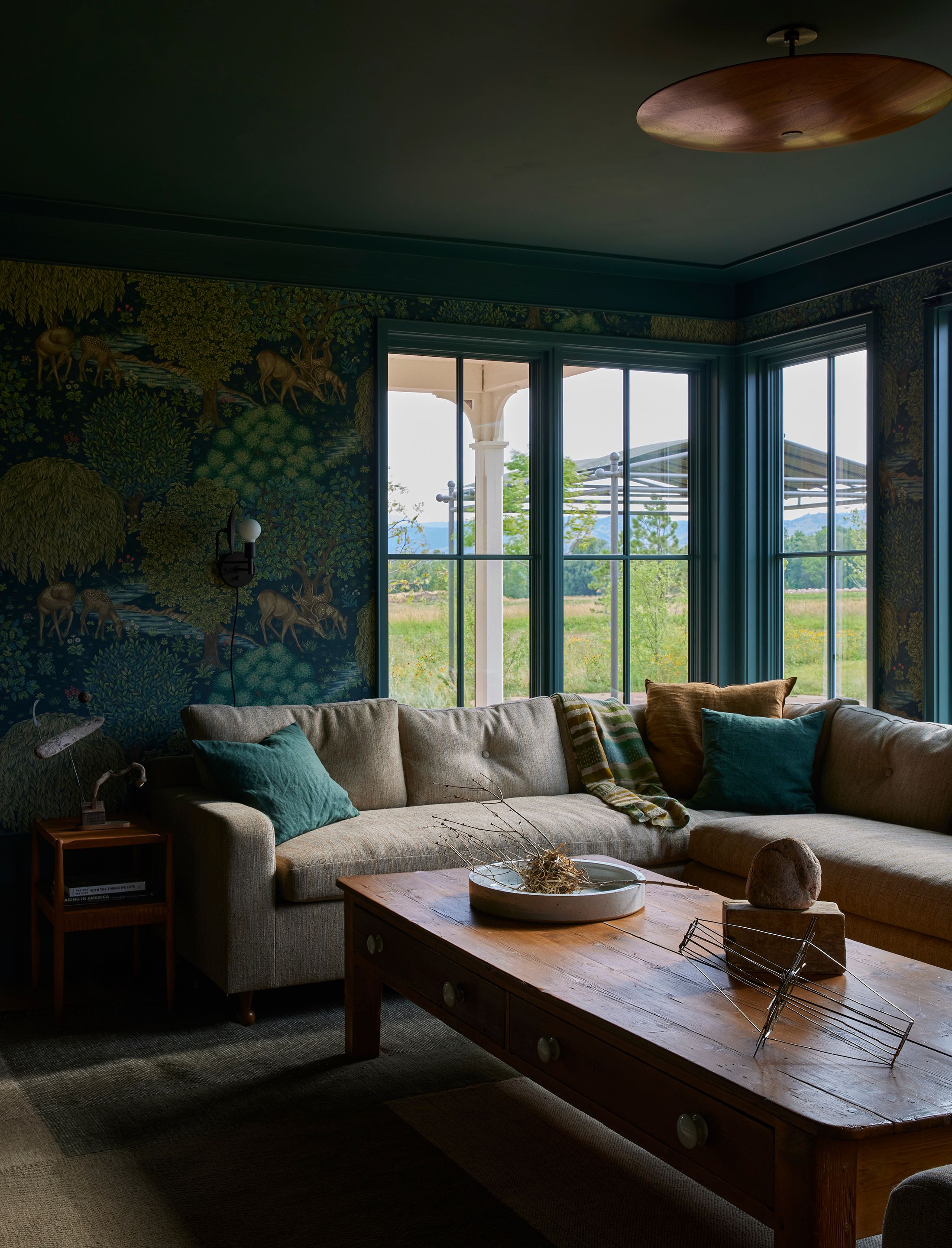 The ​​Morris & Co’s Brook wallpaper in Tapestry Blue echoes the landscape framed by the family room’s tall windows, but with a fairytale twist. The palette continues through Maison de Vacances crumpled washed-linen vice versa cushions and a custom sofa by Landed Interiors upholstered in a Larsen fabric. The coffee table, which fits perfectly between the sectional, was meant to be—it was one of the client’s own growing up.