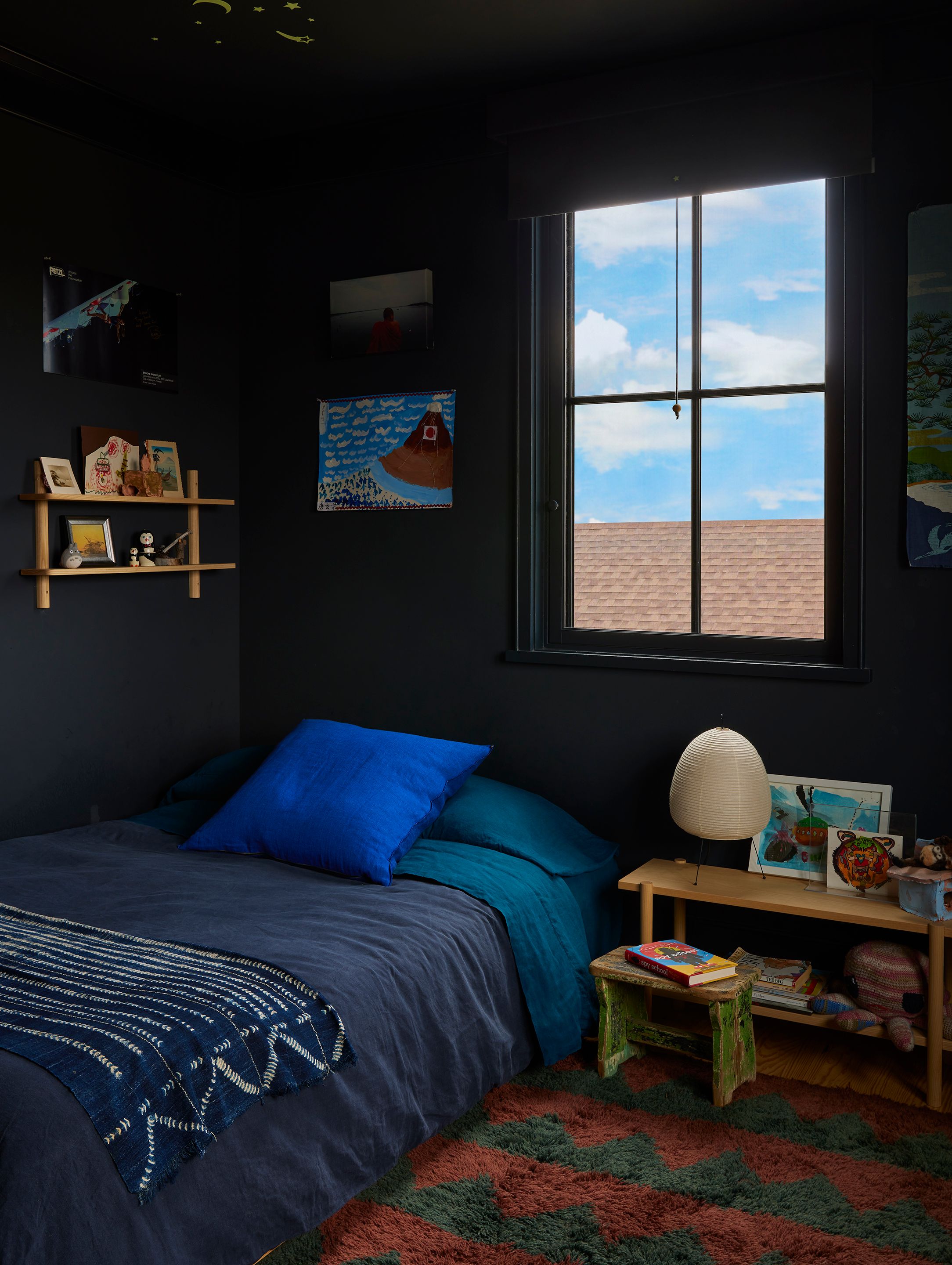 In one of the two kids’ bedrooms, a Maison de Vacances crumpled washed linen vice versa cushion in cobalt is bright as a star against linen bedding by Once Milano (duvet in petrol blue) and Hawkins New York (sheets in peacock and navy). Against the walls painted in Railings by Farrow & Ball is a double floating shelf in white ash by Kroft. Table lamp is an Akari light sculpture. Rug is Massif in oxblood and nightfall by Beni.