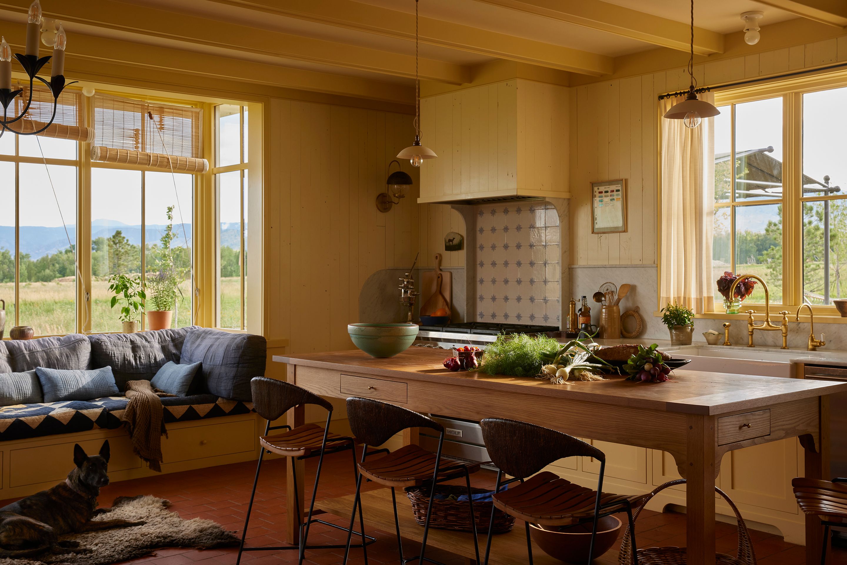 The cooking area of the kitchen is anchored by a custom island designed by Landed Interiors using a piece from Petersen Antiques. The stools are Iron Arthur Umanoff. The Wolf range is gas. The pendants are large plain skullcap porcelain by deVOL, and a double-bowl fireclay sink is Shaws via House of Rohl, fitted with an Ionian tap with rinse faucet, also by deVOL.