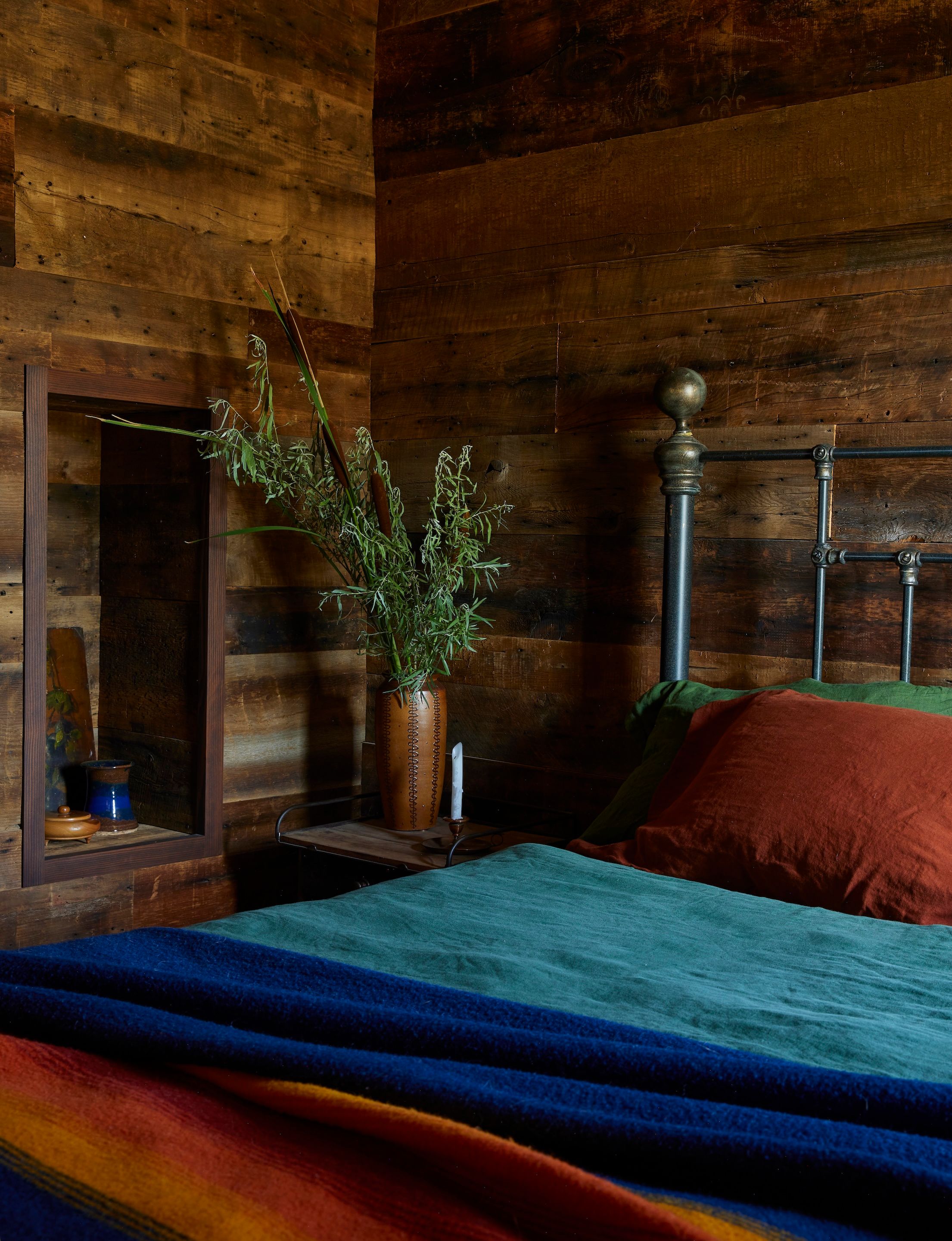 The lavish golden-brown of reclaimed board paneling lines the cabin bedroom. The linen bedding in sequoia, forest, and green is by Once Milano. The Grand Canyon National Park blanket is Pendleton and the bed frame is the clients’ own.