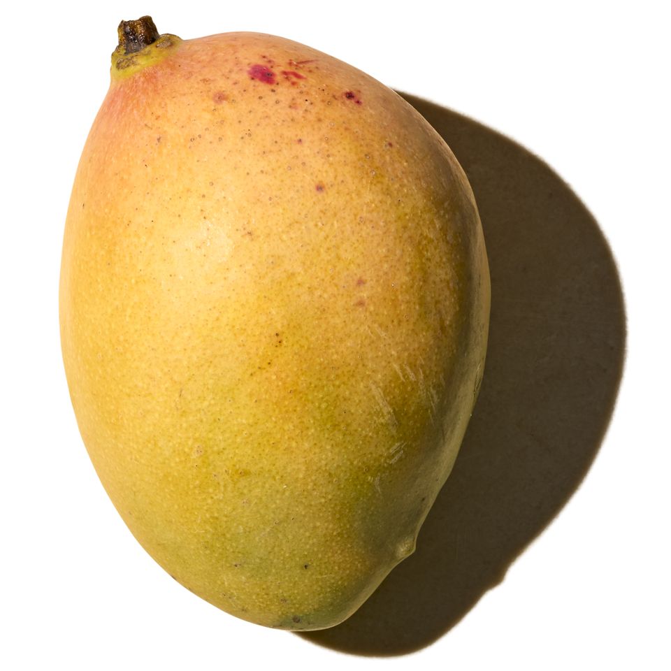A single mango from an elevated angle casting a shadow
