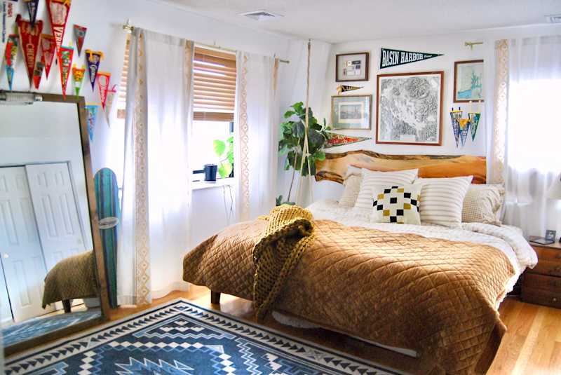 Cozy bedroom featuring a large bed with a brown quilt, decorative pillows, a patterned rug, and wall art.